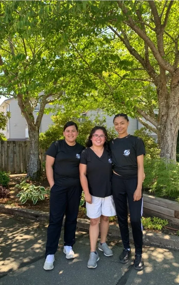 Three Crystal Care team members in uniform under a leafy tree